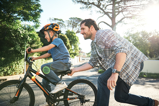 Shot of a young man teaching his son how to ride a bike