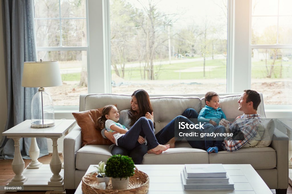House + love = home Shot of a happy young family of four relaxing together on the sofa at home Family Stock Photo