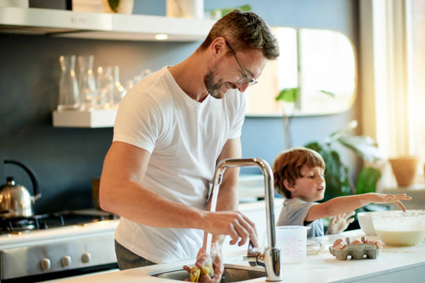 The boys are bonding Shot of a father and his adorable son baking together at home wash dishes stock pictures, royalty-free photos & images