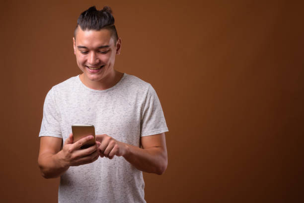 istock Studio shot of young handsome multi-ethnic man using mobile phone against colored background 854467960