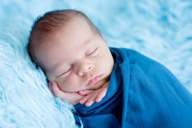 istock Cute baby boy, peacefully sleeping wrapped in blue wrap 854468778