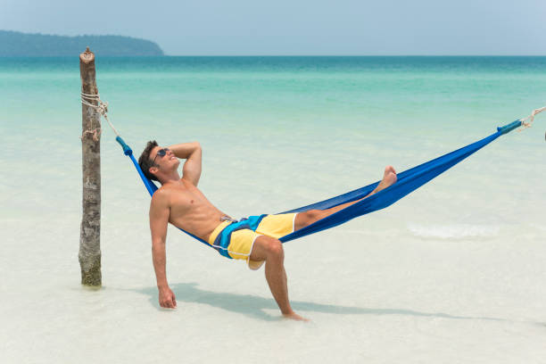 istock Handsome Man relaxing in a Hammock on a secluded Beach on Vacation 854468994