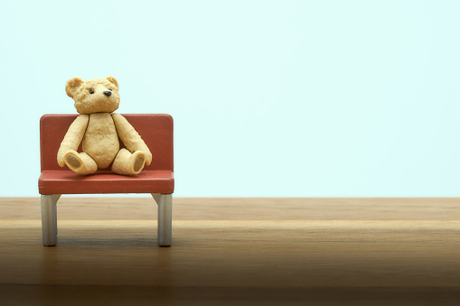 Teddy bear models and chair models Put on the right side of the picture on the wooden floor with vintage tones. Expressing the loneliness. copy space.