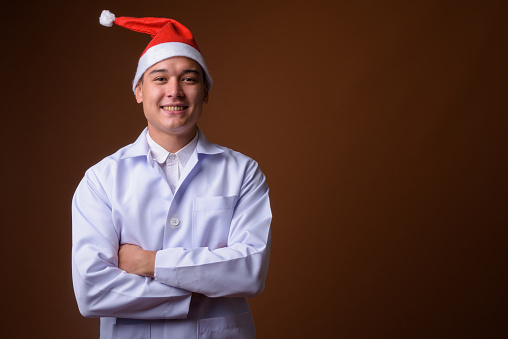 Studio shot of young handsome multi-ethnic man doctor ready for Christmas against colored background horizontal shot