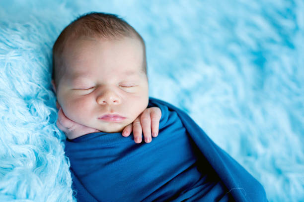 istock Cute baby boy, peacefully sleeping wrapped in blue wrap 854478868