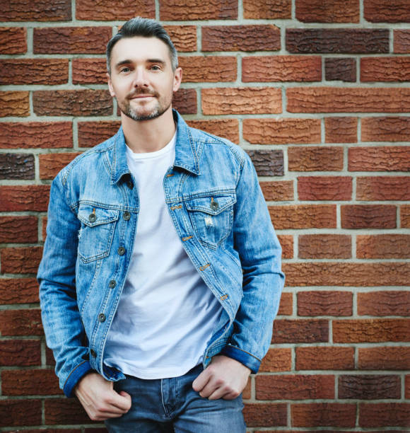 With good basics you’ll have endless options Cropped shot of a handsome man posing against a brick wall denim jacket stock pictures, royalty-free photos & images