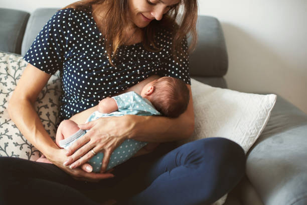 la giovane madre allatta il suo bambino, tenendolo tra le braccia - succhiare foto e immagini stock