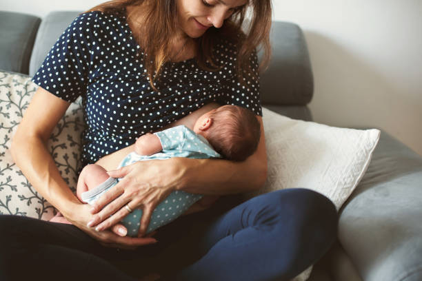 Young mother breastfeeds her baby, holding him in her arms Young mother breastfeeds her baby, holding him in her arms and smiling from happiness babyhood photos stock pictures, royalty-free photos & images