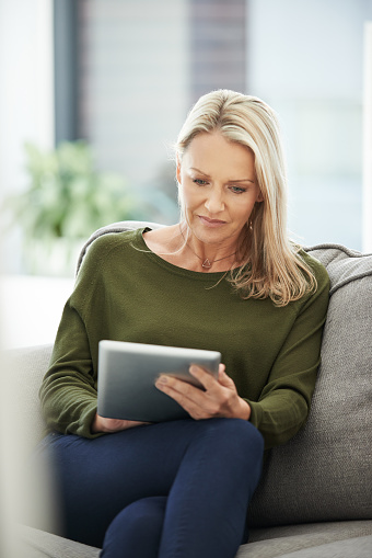 Shot of a mature woman using a digital tablet at home