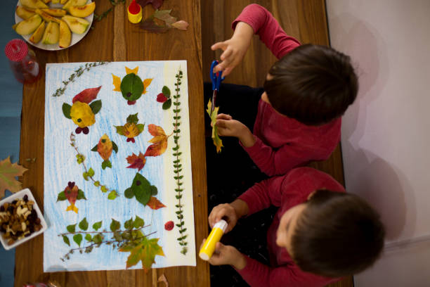 istock Sweet children, boys, applying leaves using glue 854488948
