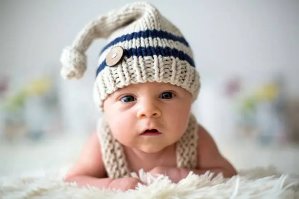 Photo of Little newborn baby boy, looking curiously at camera