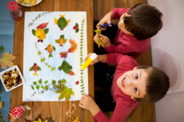 istock Sweet children, boys, applying leaves using glue 854489982