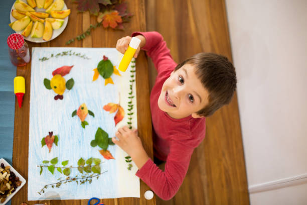 istock Sweet child, boy, applying leaves using glue 854495690