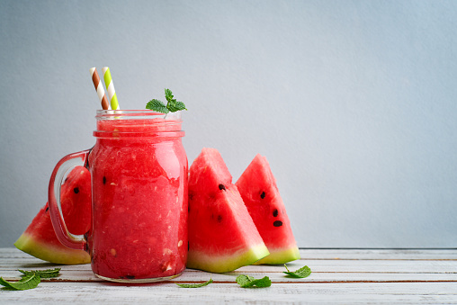 Watermelon smoothie in  jars with fresh watermelon slices on blue background