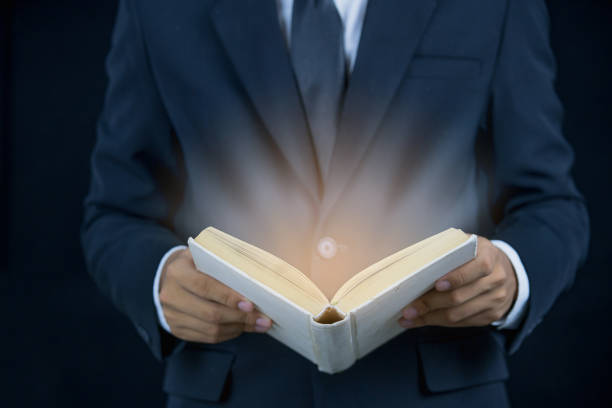 istock man wearing a suit reading a book on black background 854519240