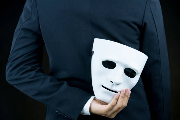 istock businessman hide the white mask in the hand behind his back on black background. 854519428