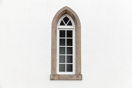 Window in white stone wall, Gothic Revival architecture style. Background photo texture