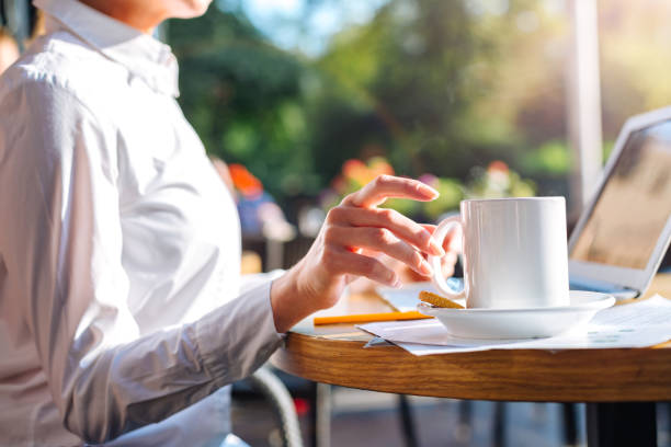istock Female hands taking a cup of coffee in open-air cafe 854559414