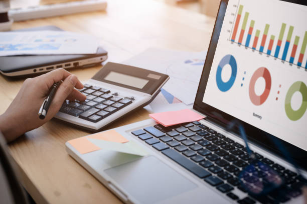 mujer de negocios utiliza una calculadora para calcular cifras de rendimiento de la empresa, gráficos los gráficos mensuales para la reunión. - finanzas domésticas fotografías e imágenes de stock