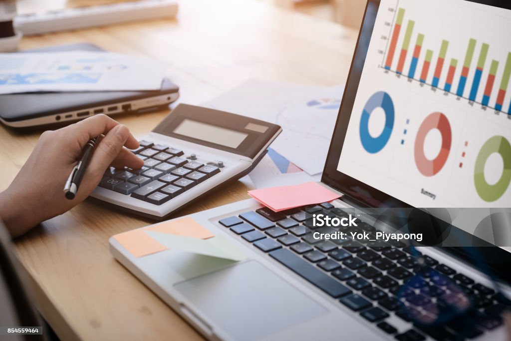 business woman uses a calculator to calculate the company's performance figures, graphs the monthly graphs for the meeting. Home Finances Stock Photo