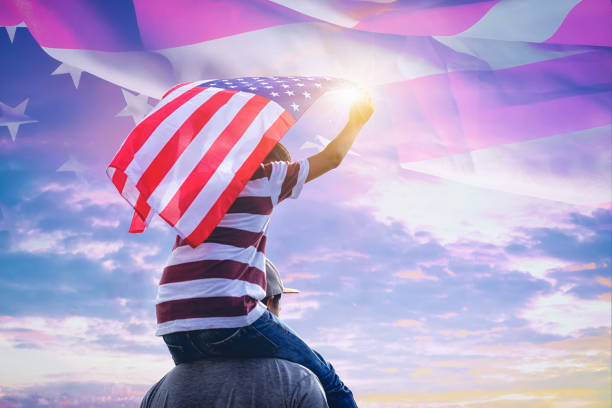 niño feliz con un hande celebró la bandera americana en pie bajo el sol de verano. estados unidos celebran 4 de julio - d�ía de la independencia. - fourth of july family flag american flag fotografías e imágenes de stock