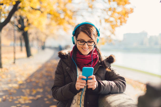 istock Smiling woman texting in the park during autumn 854571736