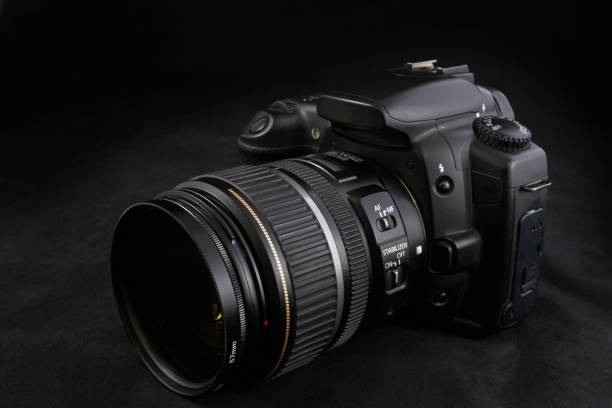 istock One black camera with zoom lens isolated on black background 854583476