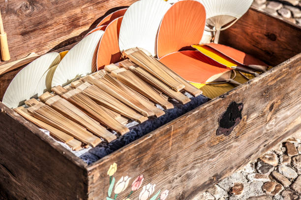 Setting of handheld fans for wedding guests. Old Trunk with wooden folding fans and bamboo rigid fans