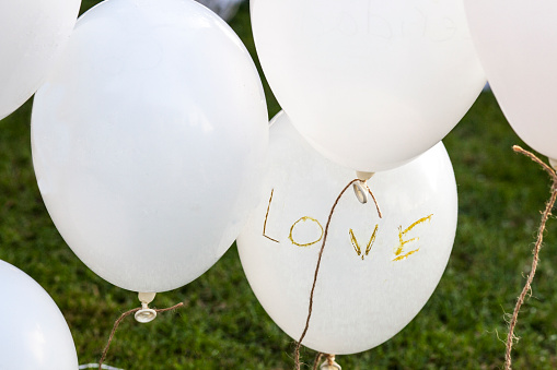White balloons over grass saying 'Love' at a wedding reception. Vintage decoration for weddings