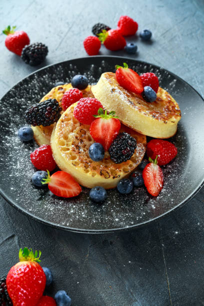 istock British Crumpets breakfast with blueberries, strawberries, blackberries, raspberries drizzled with icing sugar 854595892