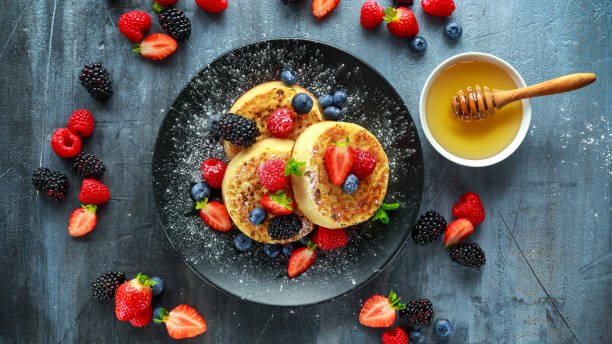 British Crumpets breakfast with blueberries, strawberries, blackberries, raspberries drizzled with icing sugar