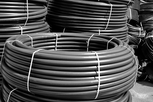 Coiled black plastic pipes stored outdoors