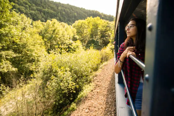 Photo of The attractive 15-years-old teenager girl enjoy the train ride through the scenic landscapes.