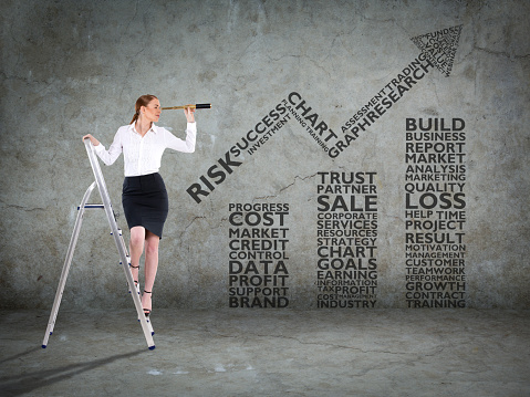 Businesswoman standing on ladder and looking through spyglass in front of business bar graph word cloud
