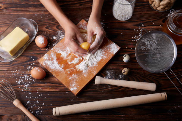 istock Top view of hands holding a cracked egg with yolk on a table background. Baking and dough making. 854632266