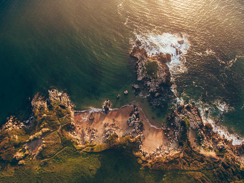 An aerial view of a small rocky beach at sunset