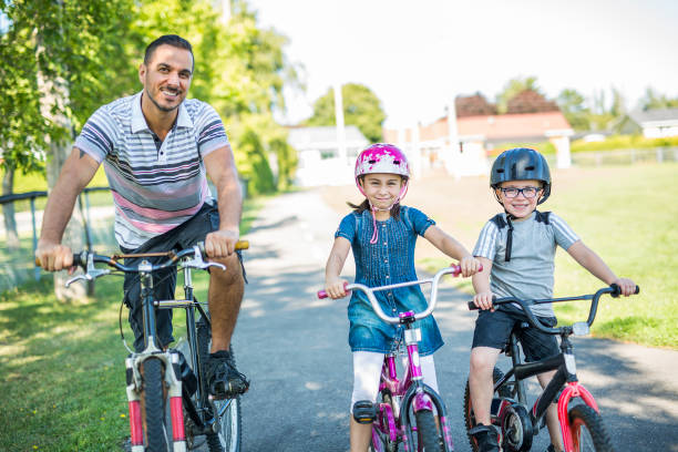 istock Dad With Daughter Son Riding Bikes In Park 854653658