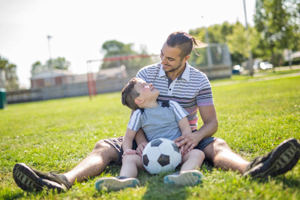 istock man with child playing football on field 854656318