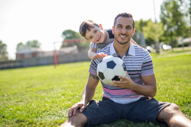 istock man with child playing football on field 854656452