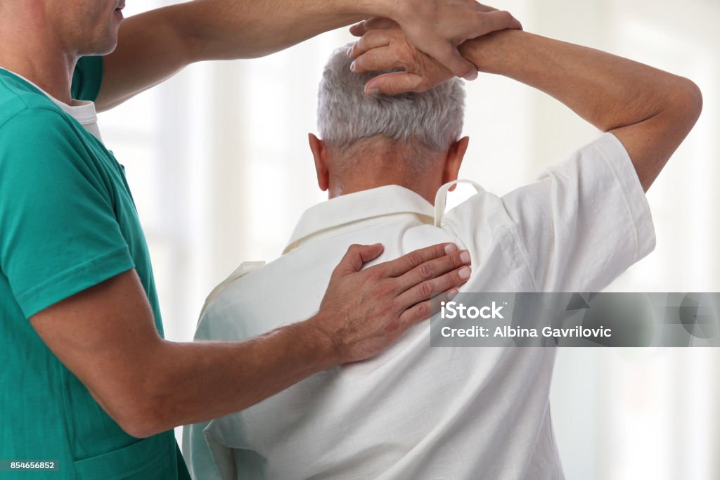 Senior man having chiropractic back adjustment. Osteopathy, Physiotherapy, pain relief concept Senior Adult Stock Photo