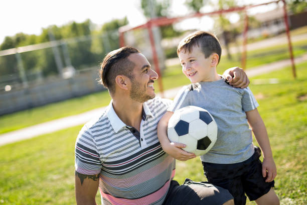 istock man with child playing football on field 854656866