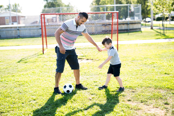 istock man with child playing football on field 854657686