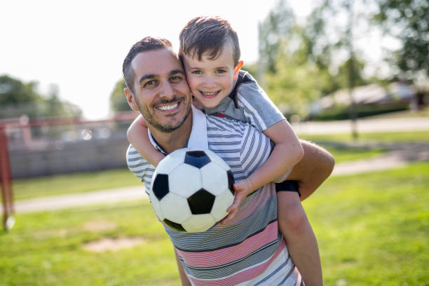 man with child playing football on field