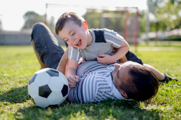 istock man with child playing football on field 854658472