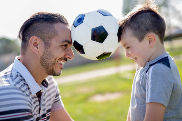 istock man with child playing football on field 854660574