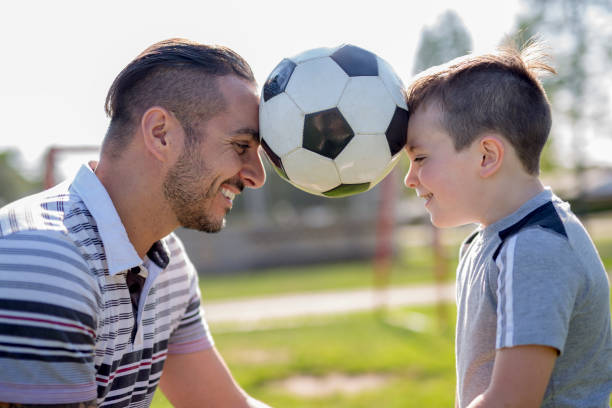 istock man with child playing football on field 854662704