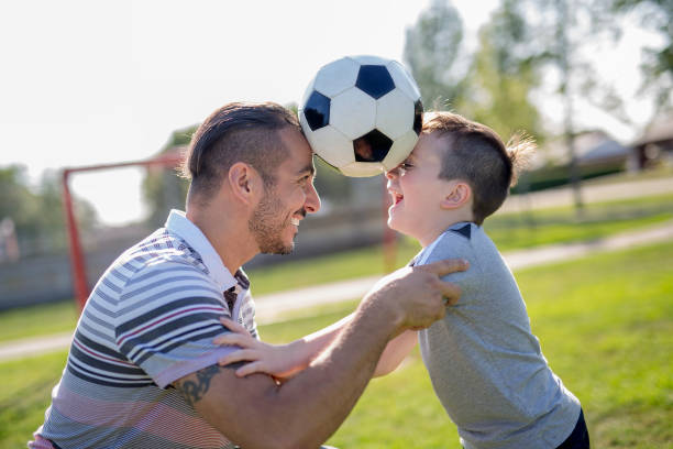 istock man with child playing football on field 854662746