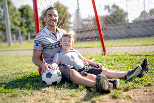 istock man with child playing football on field 854663118