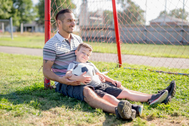 istock man with child playing football on field 854663218