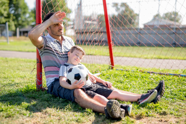 istock man with child playing football on field 854663276